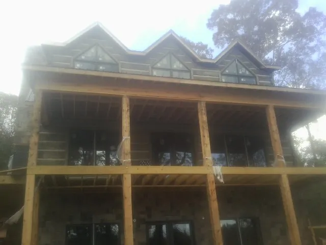 Dormers and porch framing on a large log home under construction — Roof Coating work by our crew in Bunker Hill