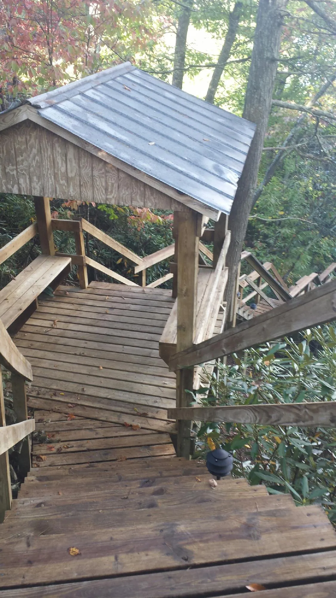 Metal roofed shelter over wooden steps on a wooded walkway — Skylight Repair & Installation work by our crew in Bunker Hill